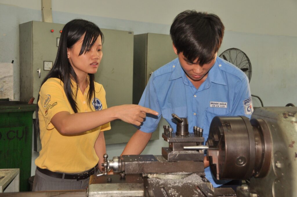 Giảng viên hướng dẫn sinh viên vận hành máy tiện tại xưởng cơ khí